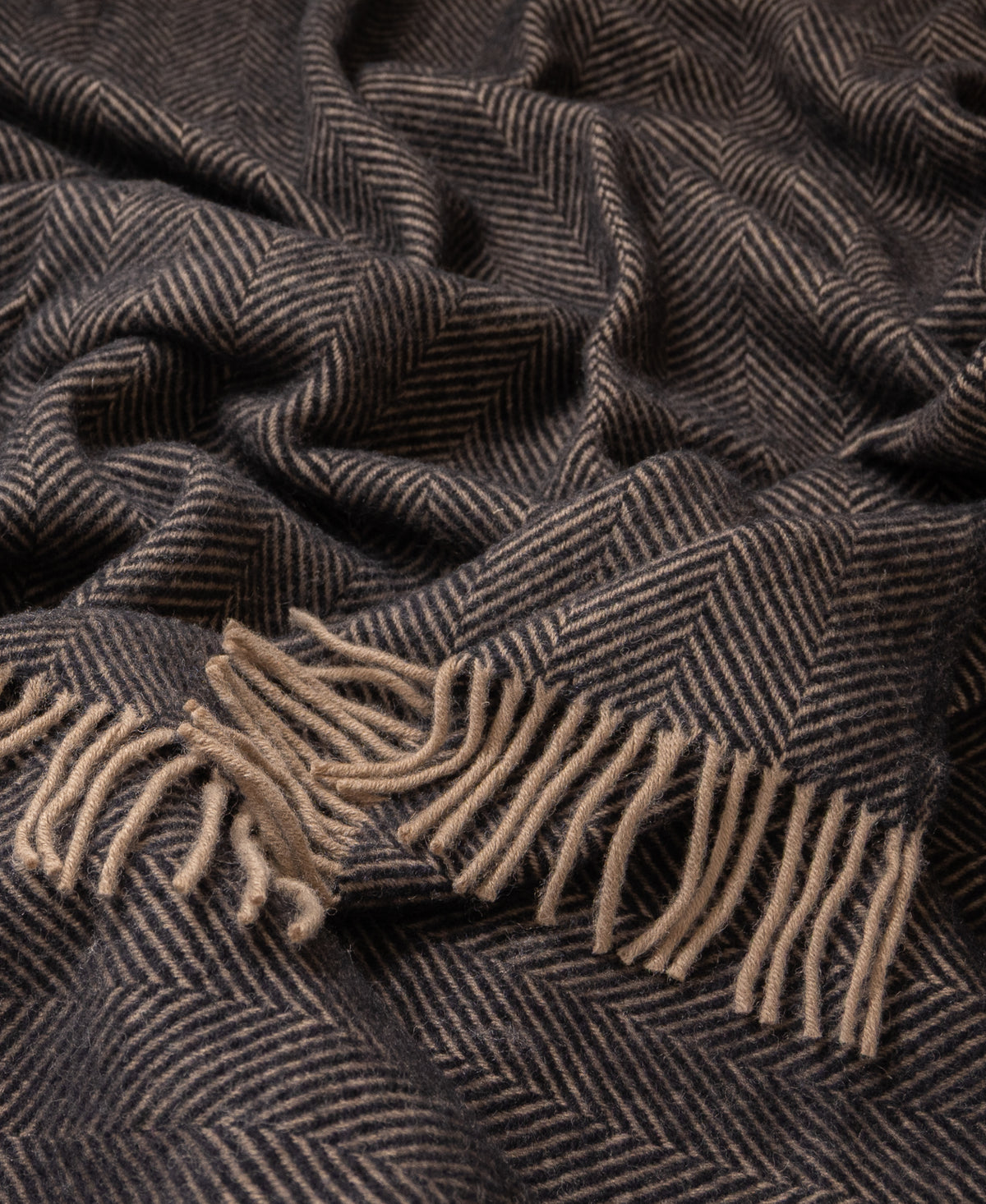 Black and tan herringbone pure new wool throw blanket featuring a soft, textured weave and decorative fringe edges.