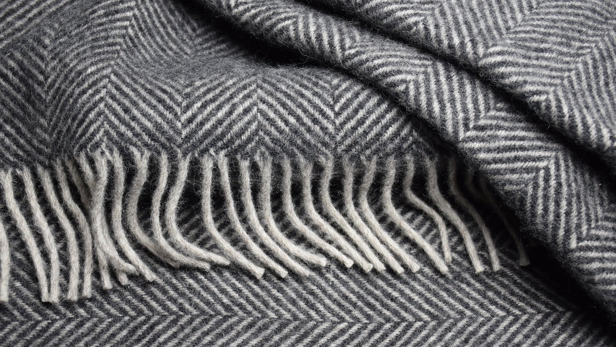 Charcoal and white herringbone pure new wool throw blanket with soft fringe detail, woven in a classic British style.