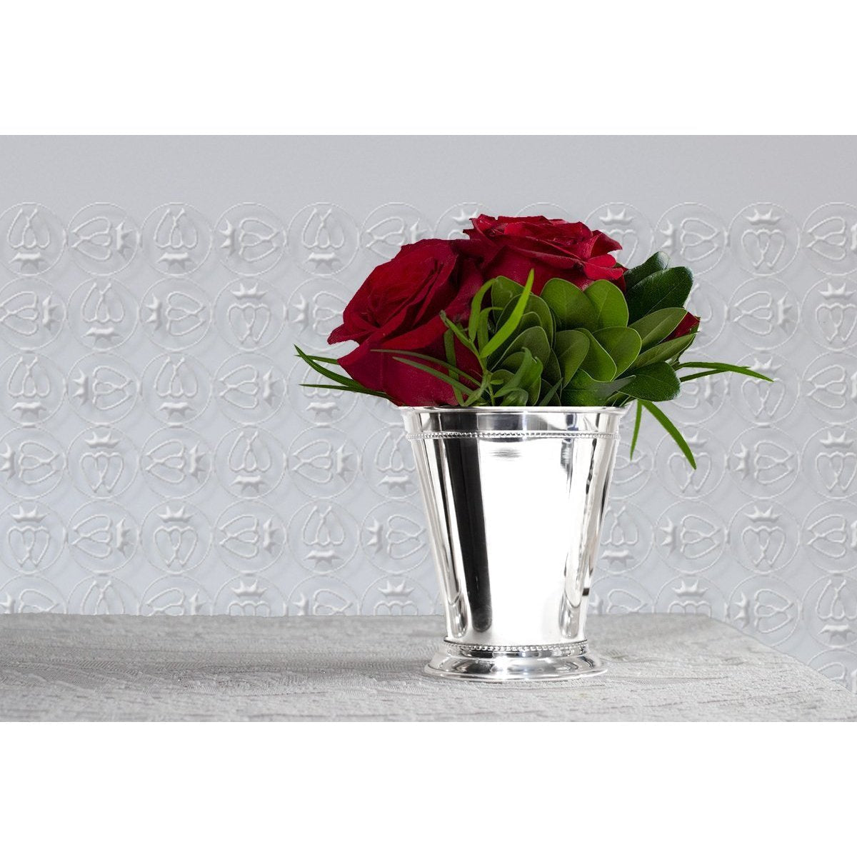 Handmade silver-plated copper mint julep cup with decorative beaded trim holding a bouquet of red roses.