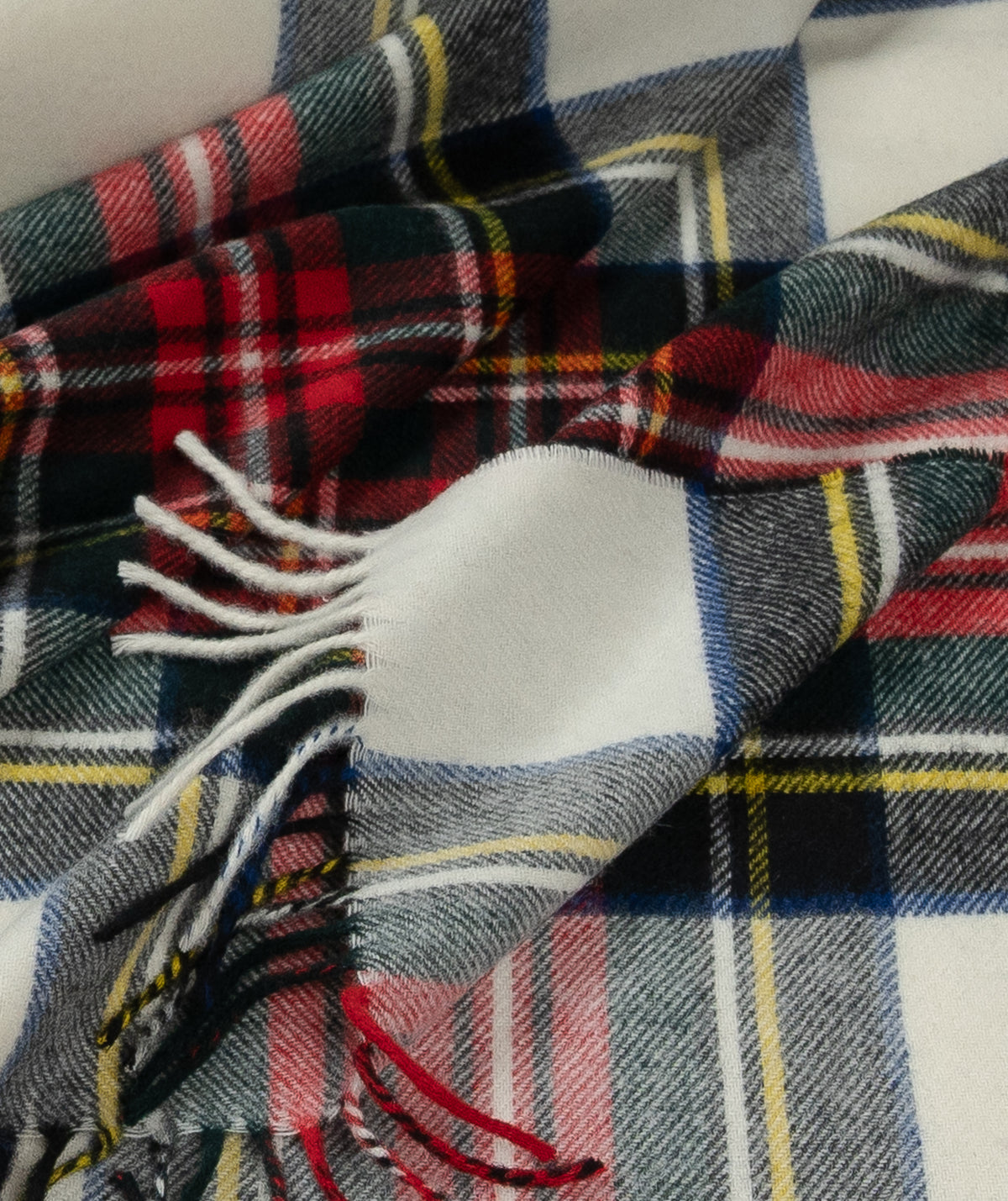 Dress Stewart tartan merino wool throw with fringed edges in red, green, white, and yellow plaid.