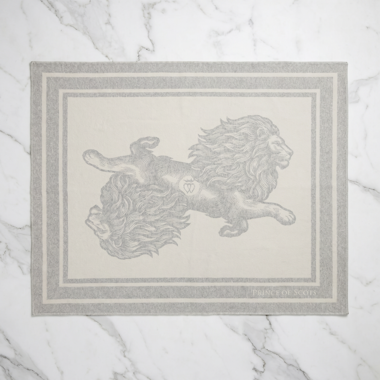A rectangular area rug with a light gray border and a central illustration of two lions facing each other, laid flat on a white marble surface.