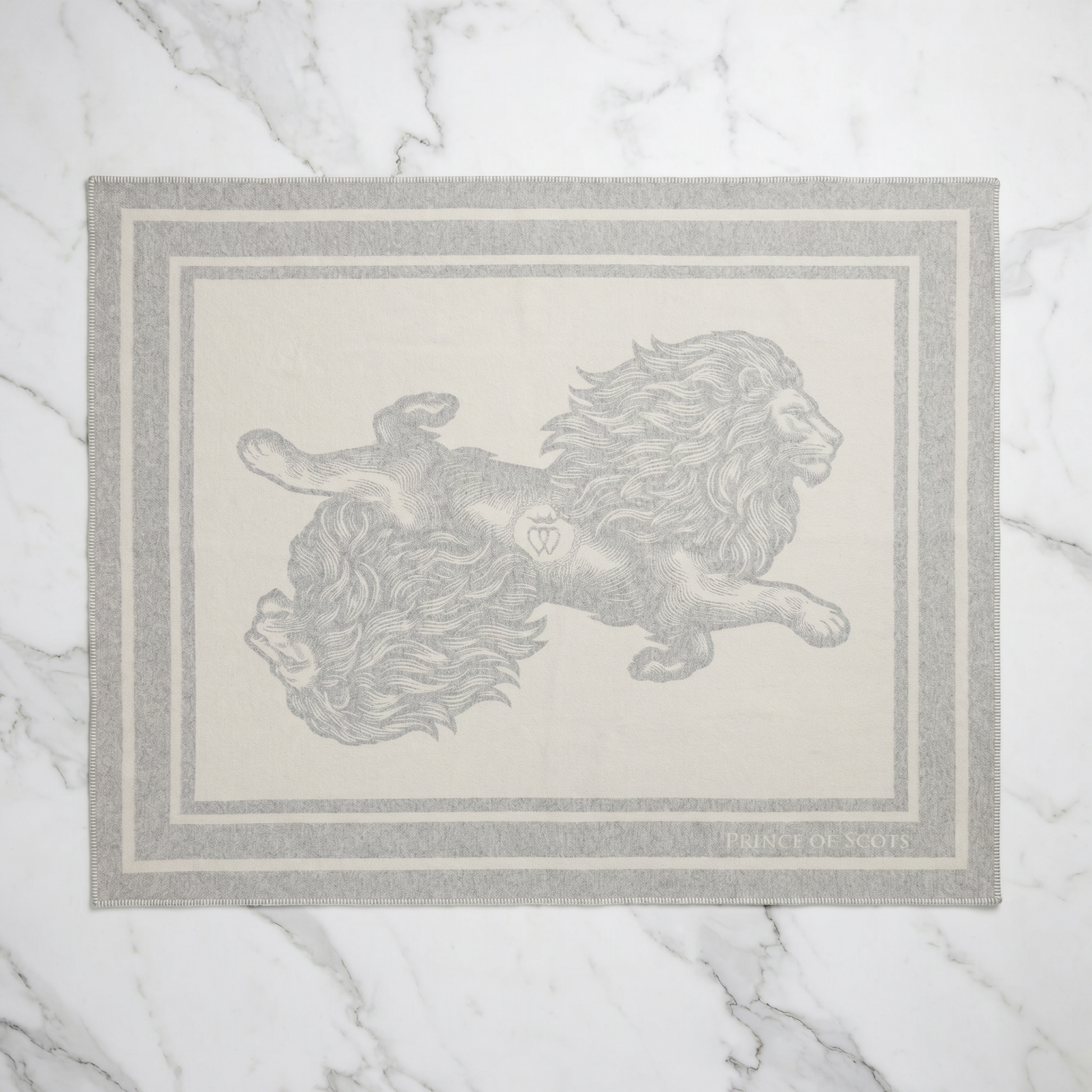 A rectangular area rug with a light gray border and a central illustration of two lions facing each other, laid flat on a white marble surface.