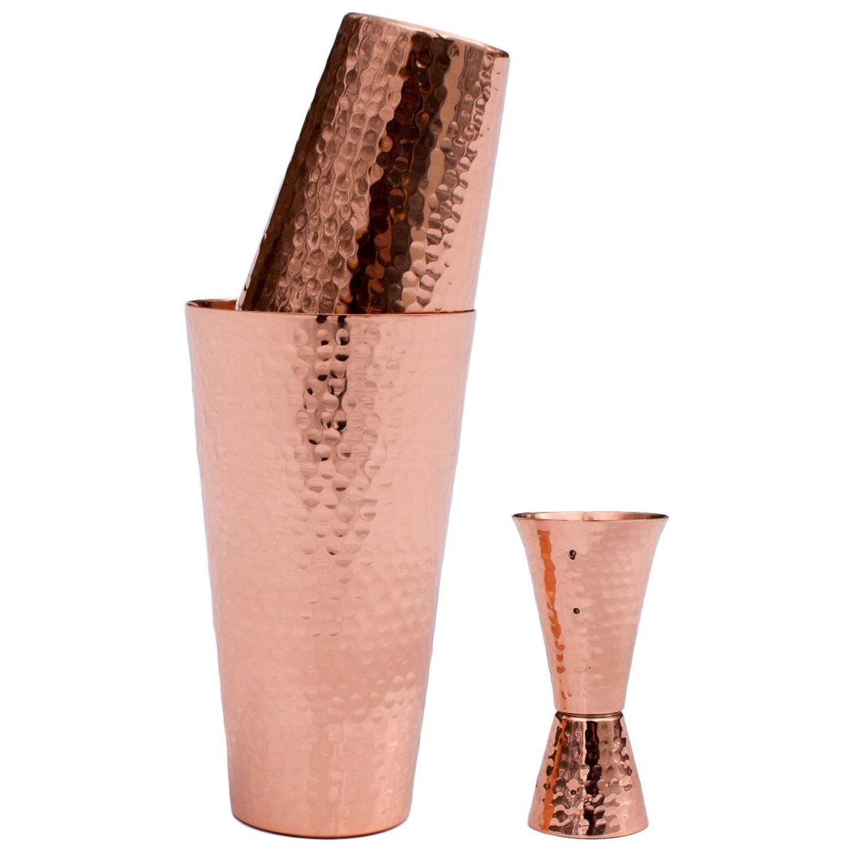 Hammered pure copper Boston cocktail shaker set with a matching double-sided jigger on a white background.